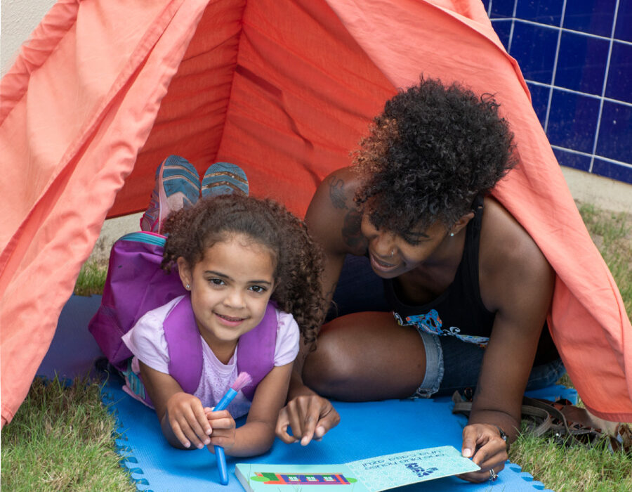 Adult and child read a book in a play tent
