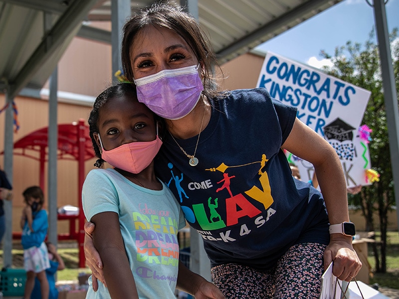 Pre-K 4 SA staff member embraces student while wearing masks