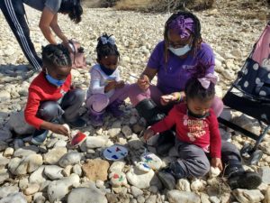 children and teacher explore rocks outside to make artwork
