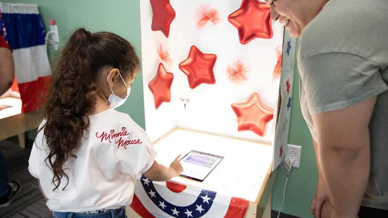child voting at a booth with stripes and stars