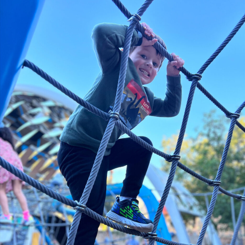 a child climbing an outdoor jungle gym