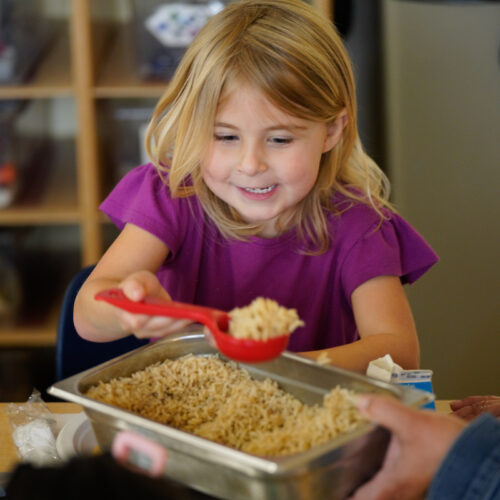 a young girl scoops a serving of rice