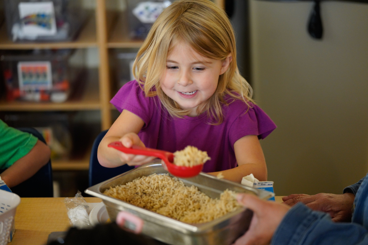 a young girl scoops a serving of rice