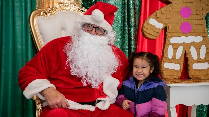 Santa and a child pose for a festive photo.