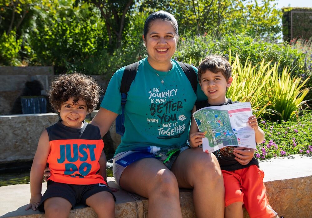 A woman and two children sitting on a stone wall.