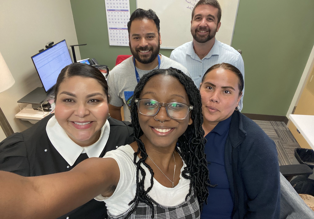 staff huddle and smile for a selfie