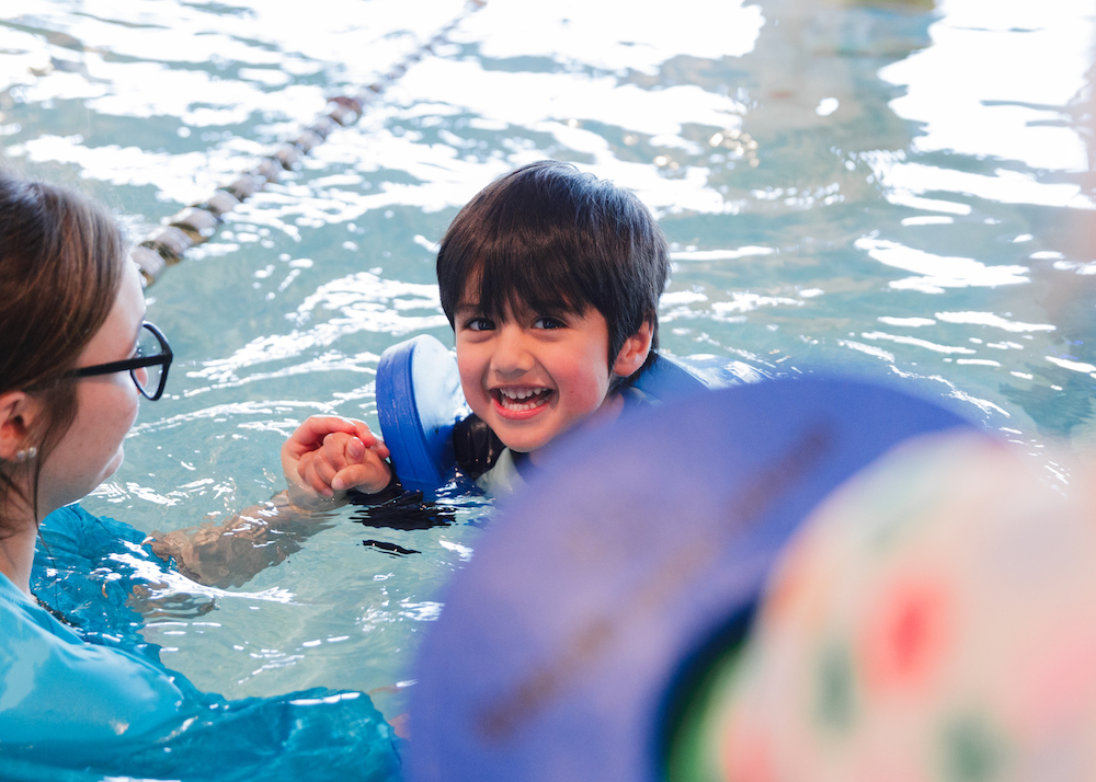 A young boy with floaties on in a pool