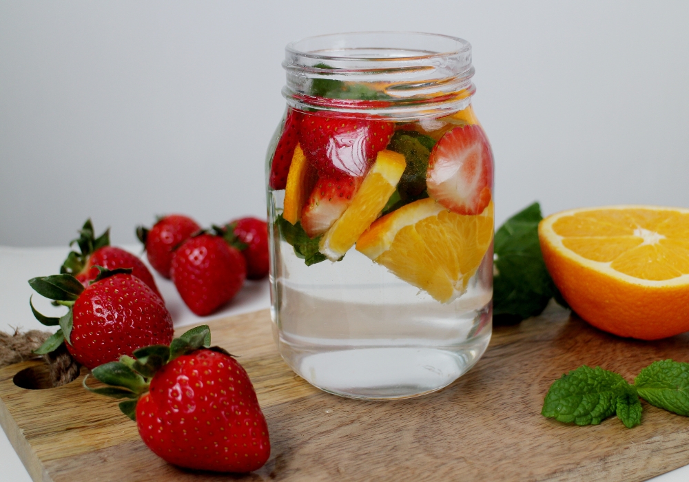 A jar of water infusing with oranges and strawberries