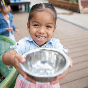 A child holds up a bowl of water