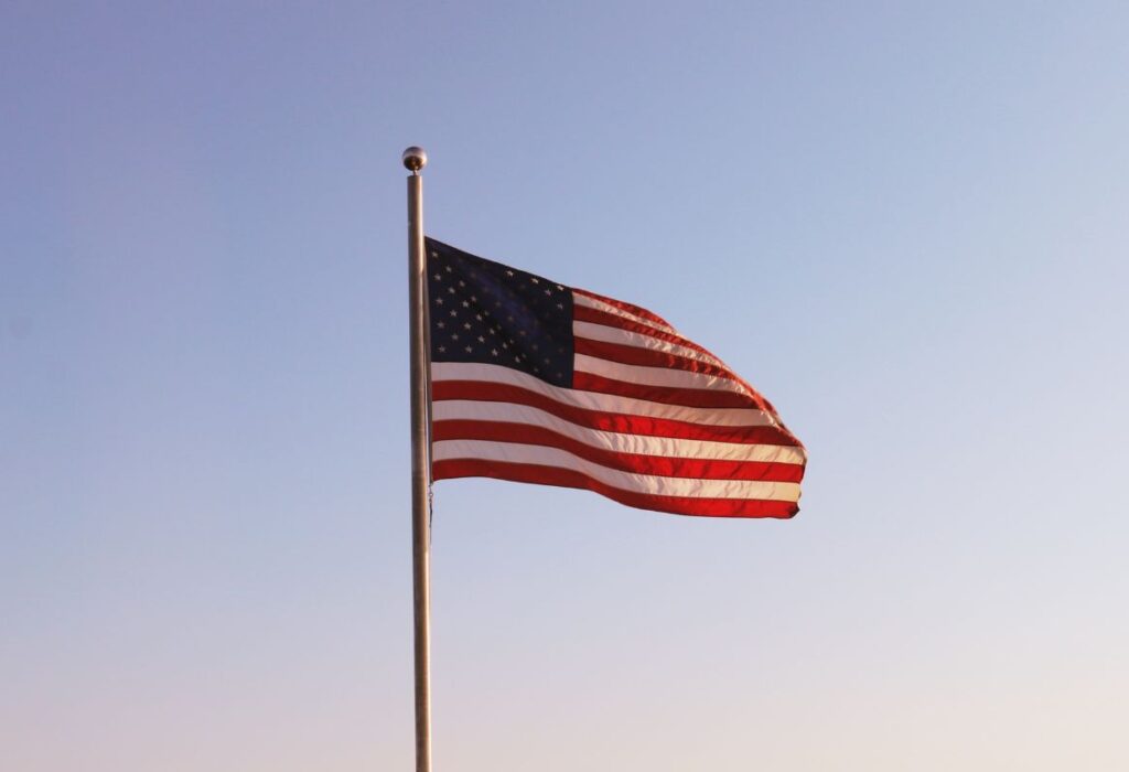 An American flag on a flagpole in the wind during dusk.