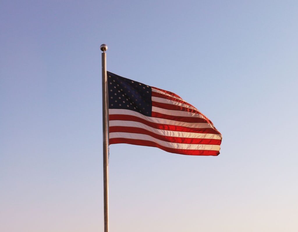An American flag on a flagpole in the wind during dusk.