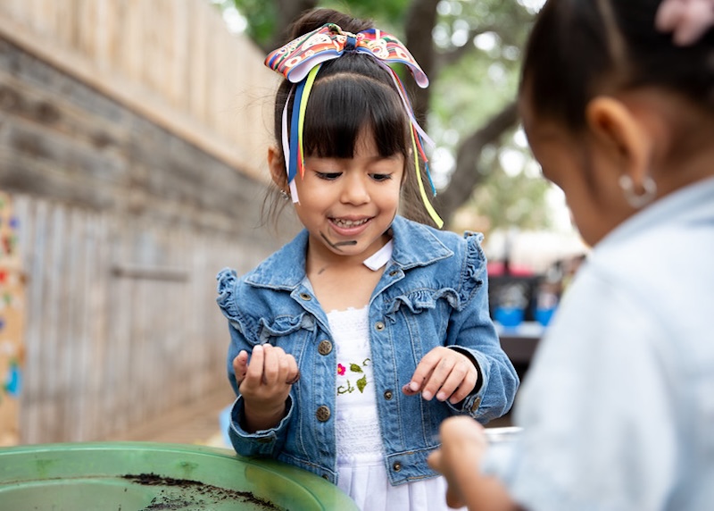 two toddlers explore soil in the garden