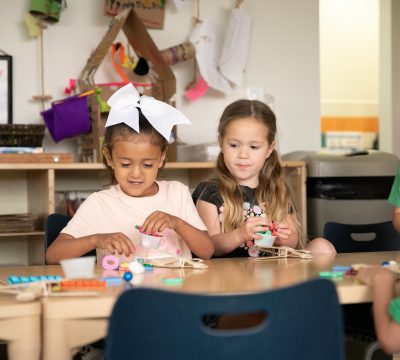 young children play with popsicle sticks and other items at a table