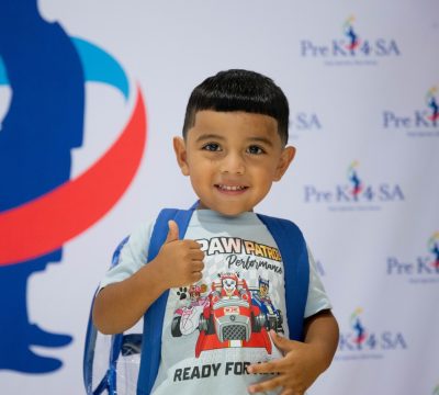 Young boy smiling with backpack at Pre-K 4 SA program event.
