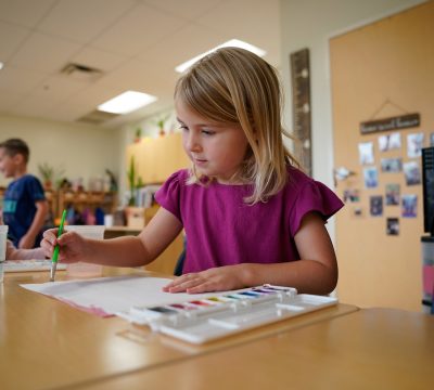 a young girl paints with watercolors