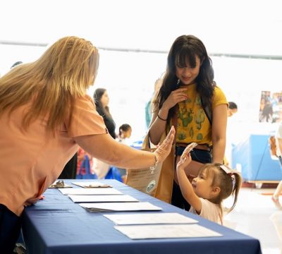 a small girl gives a high five to an adult at a preschool event