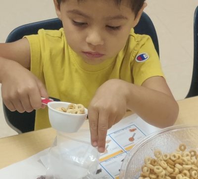 a young child pours cheerios into a bag