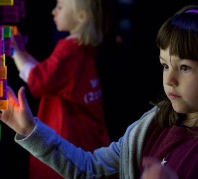 a young girl plays with a light brite in a dark room