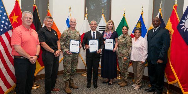 Group of diverse professionals and military personnel holding awards at Pre-K 4 SA event.